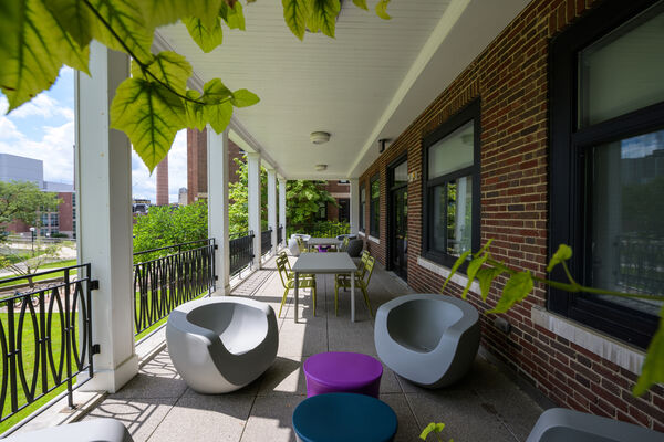 A covered patio with seating at Couzens Hall