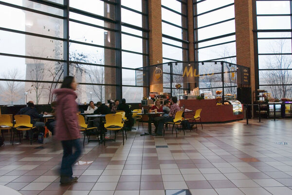 A person walking through Duderstadt Center in front a wall of windows