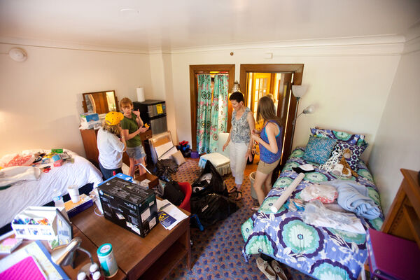 A group of women socializing in a dorm room with colorful bedding in Martha Cook